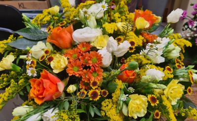 Casket spray in cheery colour combination of seasonal flowers and foliage's in yellows and oranges